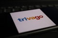 Closeup of mobile phone screen with logo lettering of trivago online travel agency on computer keyboard