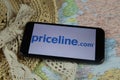 Closeup of mobile phone screen wit logo lettering of online booking travel agency priceline.com with sun hat and map Royalty Free Stock Photo