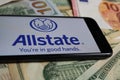 Closeup of smartphone with logo lettering of allstate insurance company on paper money currency Royalty Free Stock Photo