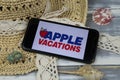 Closeup of smartphone with logo lettering of apple vacations travel agency with sun hat and shells on wood table Royalty Free Stock Photo