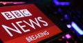 Closeup of smartphone with logo lettering of BBC breaking News on computer keyboard