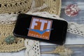 Closeup of smartphone with logo lettering of fti touristik group travel agency with sun hat and shells on wood table