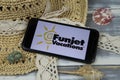 Closeup of smartphone with logo lettering of funjet vacations travel agency with sun hat and shells on wood table Royalty Free Stock Photo