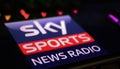 Closeup of smartphone with logo lettering of Sky Sports News Radio on computer keyboard