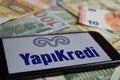 Closeup of smartphone with logo lettering of turkish yapy ve kredi bank company on paper money currency