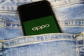 Closeup of smartphone screen with logo lettering of chinese oppo mobile phone company in blue jeans pocket