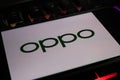 Closeup of smartphone screen with logo lettering of chinese oppo mobile phone company on computer keyboard
