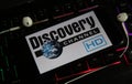 Closeup of smartphone screen with logo lettering of online tv and movie streaming service discovery channel on illuminated compute