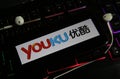 Closeup of smartphone screen with logo lettering of online tv and movie streaming service youku on illuminated computer keyboard