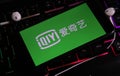 Closeup of smartphone screen with logo lettering of online tv, video and movie streaming service iqiyi on illuminated computer ke