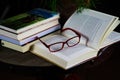 View on open book with red reading glasses and stack of travel books