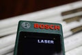 Close up of isolated Bosch laser range finder tool, blurred folding yard ruler background Royalty Free Stock Photo