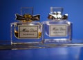 Close up of two isolated Miss Dior perfume flacons on glass, blue background