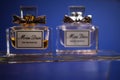 Close up of two isolated Miss Dior perfume flacons on glass, blue background