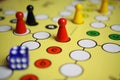 Closeup of yellow game board with colorful pieces and dice of mensch ÃÂ¤rgere dich nicht