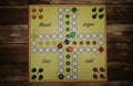 Top down view on yellow strategy game board with colorful pieces and dices of mensch ÃÂ¤rgere dich nicht, wooden background