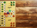 Top down view on yellow strategy game board with colorful pieces and dices of mensch ÃÂ¤rgere dich nicht, wooden background