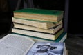 View over open book antique book about history of people on pile with yellowed old books on round wood table