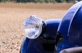 Close up of isolated silver chrome headlight of black French classic cult car 2CV in rural area