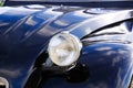 Close up of isolated silver chrome headlight of black French classic cult car 2CV in rural