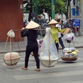  women street vendors with coolie hats and baskets carried on bamboo poles, Hanoi Vietnam 