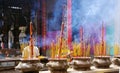 HO CHI MINH CITY, VIETNAM - JANUARY 5. 2015: Woman praying behind pots with burning and fuming incense sticks in buddhist chinese Royalty Free Stock Photo