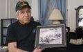 Vietnam war veteran holds an old war photo of himself.