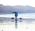 Vietnam woman in vietnamese hat walking on seacost at sunset