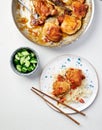 Vietnamese caramel chicken in a large bowl and 2 pieces of chicken lying on a plate. A bowl with cucumbers stands near