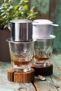 Vietnamese coffee in glass cups on old boards, phin filter and green grass background