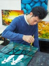 Vietnamese craftsman applying lacquer to protect painting.