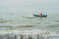 Vietnamese fisherman swims in a boat over the raging sea