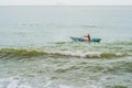 Vietnamese fisherman swims in a boat over the raging sea