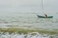 Vietnamese fisherman swims in a boat over the raging sea