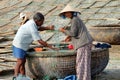 Vietnamese fishermen check fishing nets near round wicker boat Thung chai