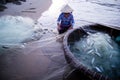 Vietnamese fisherwoman with conical hat check her nets for the catch fish from the beach