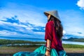Vietnamese girl sitting on the dike in beautiful sunset with blue sky in Dau Tieng lake, Tay Ninh province, Vietnam