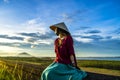 Vietnamese girl sitting on the dike in beautiful sunset with blue sky in Dau Tieng lake, Tay Ninh province, Vietnam