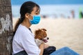 Vietnamese girl with small dog relax on the sand beach near sea on the city Danang, Vietnam Royalty Free Stock Photo