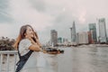 A Vietnamese girl standing by the riverbank admiring the view of Ho Chi Minh city with Bitexco Financial Tower, many buildings and