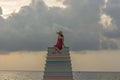 A vietnamese lady sitting on multicolored step structure at a beach