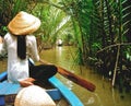 A Vietnamese lady in traditional conical hat, sits on her wooden boat in the Mekong Delta, near Ho Chi Minh city, Vietnam