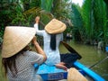 A Vietnamese ladies in traditional conical hats, sits on her wooden boat in the Mekong Delta, near Ho Chi Minh city, Vietnam