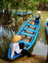 A Vietnamese lady wearing a traditional hat, sits on her wooden boat in the Mekong Delta, near Ho Chi Minh city, Vietnam