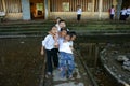 Vietnamese little boy pupils wear uniform: white t shirt, blue trousers standing on flooded school yard front of poor building