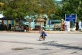 Vietnamese little girl riding bike cross road from school at noon