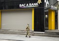 A Vietnamese local bank office closes on weekendA volunteer security guard man with face mask walking pass a Vietnamese local bank