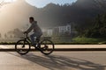 Vietnamese male in coat is cycling a bicycle around the lake