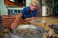 Vietnamese man prepares prawns for drying in a metal container
