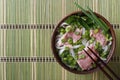 Vietnamese Pho Bo soup with beef rare, rice noodles and fresh he